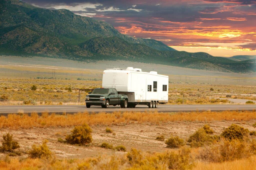 An RV heads down a scenic road at sunset.