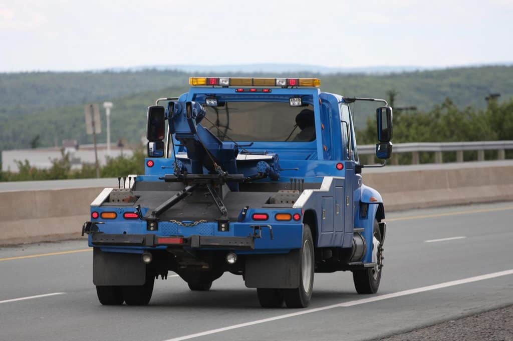 Blue tow truck on a call to pick up a car