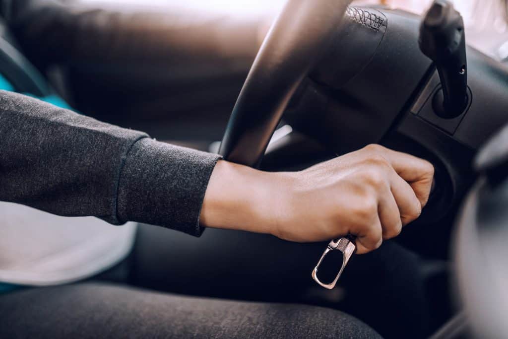 Close up of pregnant woman starting car. Other hand on steering wheel. Selective focus on hand with keys, My Car Won't Start But It Clicks [5 Potential Causes]