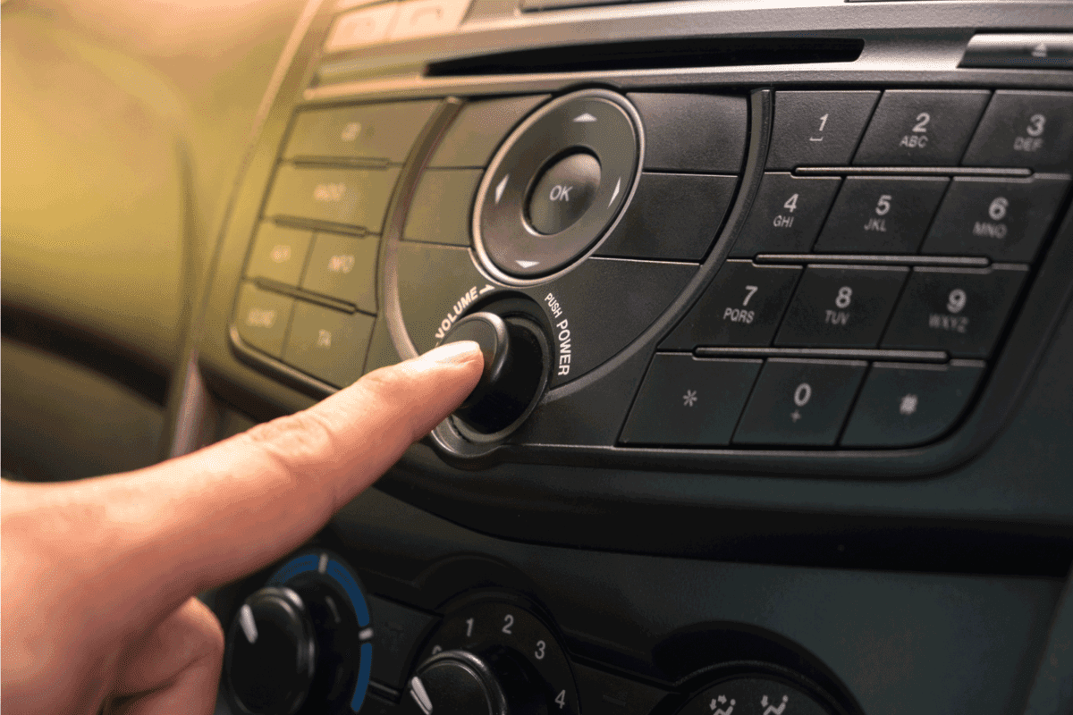 Hand Pushing the power button to turn on the car stereo system