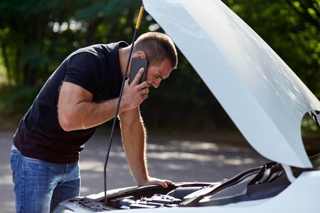 Man calling someone for help with his broken car