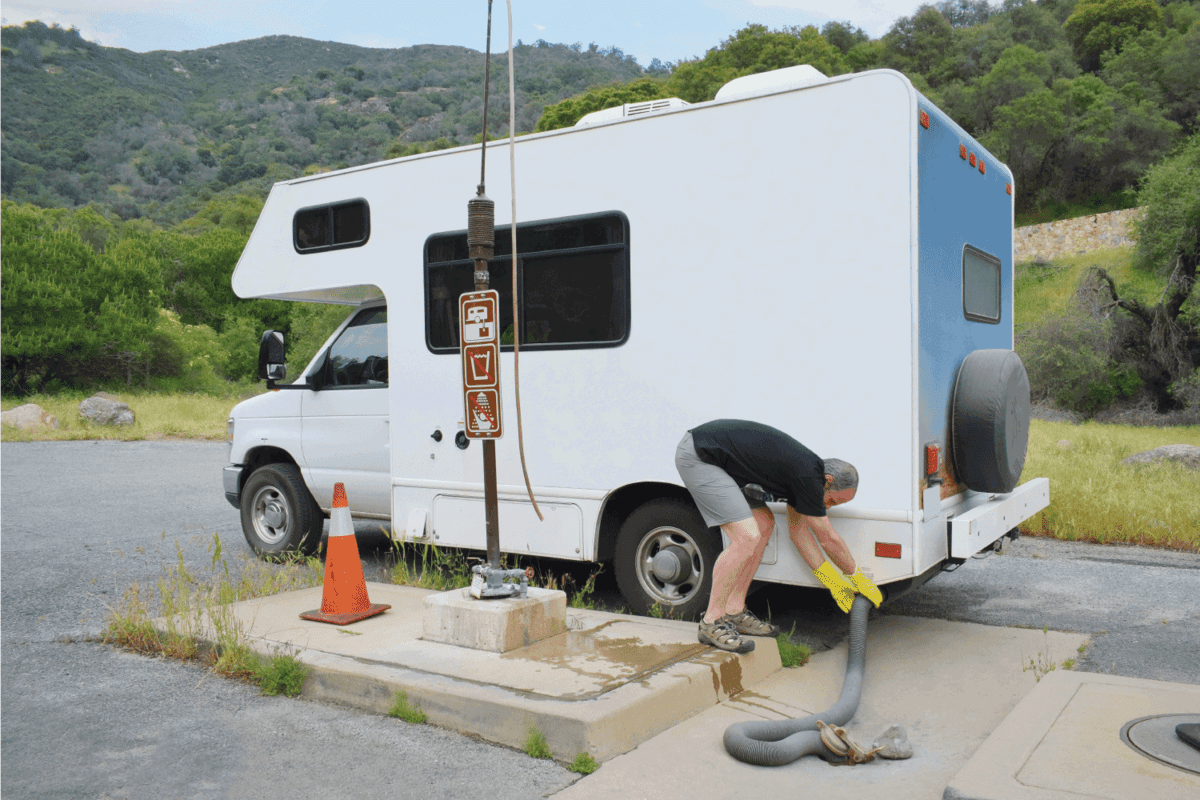 Man connecting RV vehicle to dumping station, waste disposal