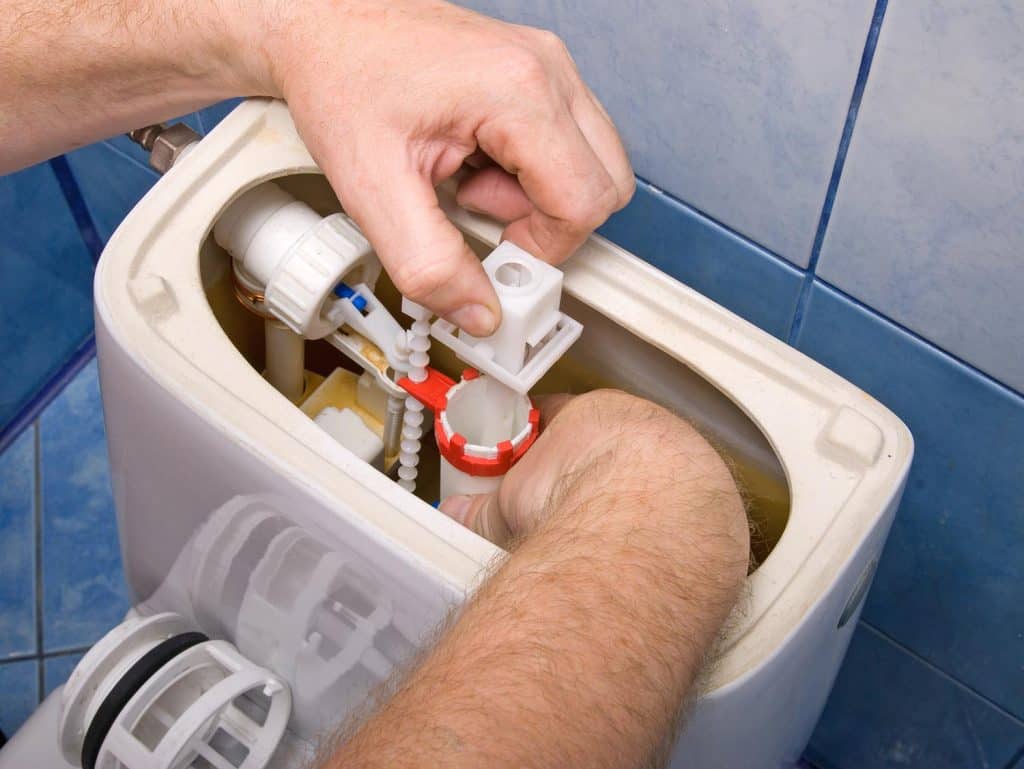 Plumber repairing the mechanism of a toilet