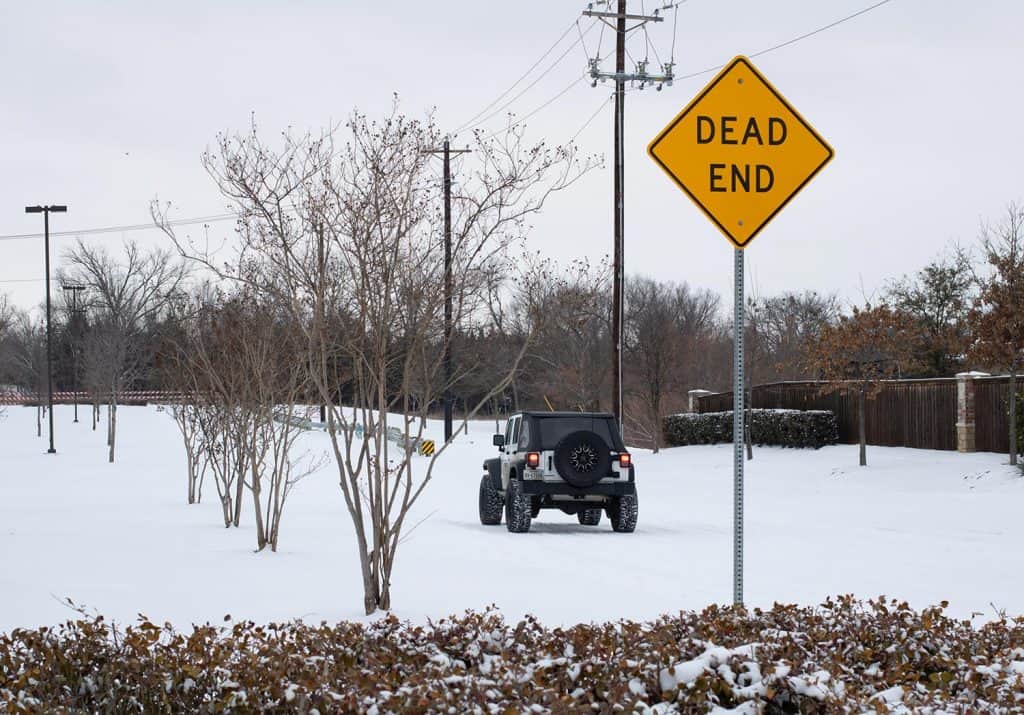 Street view of Mckinney covered by heavy snow with a jeep rubicon driving on the road