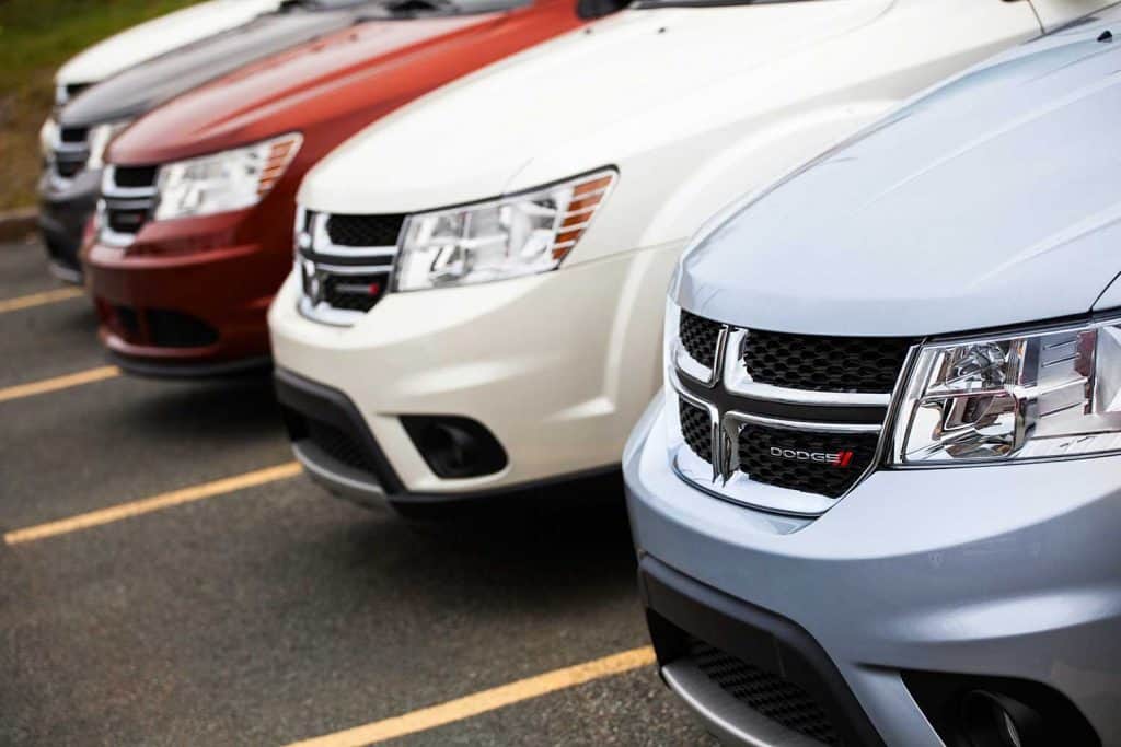 Various colors of Dodge Journey vehicles in a row at a car dealership
