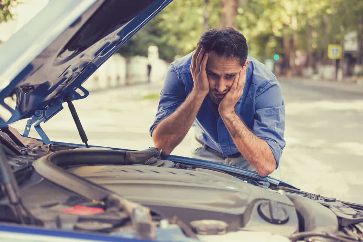 Young stressed man having trouble with his broken car