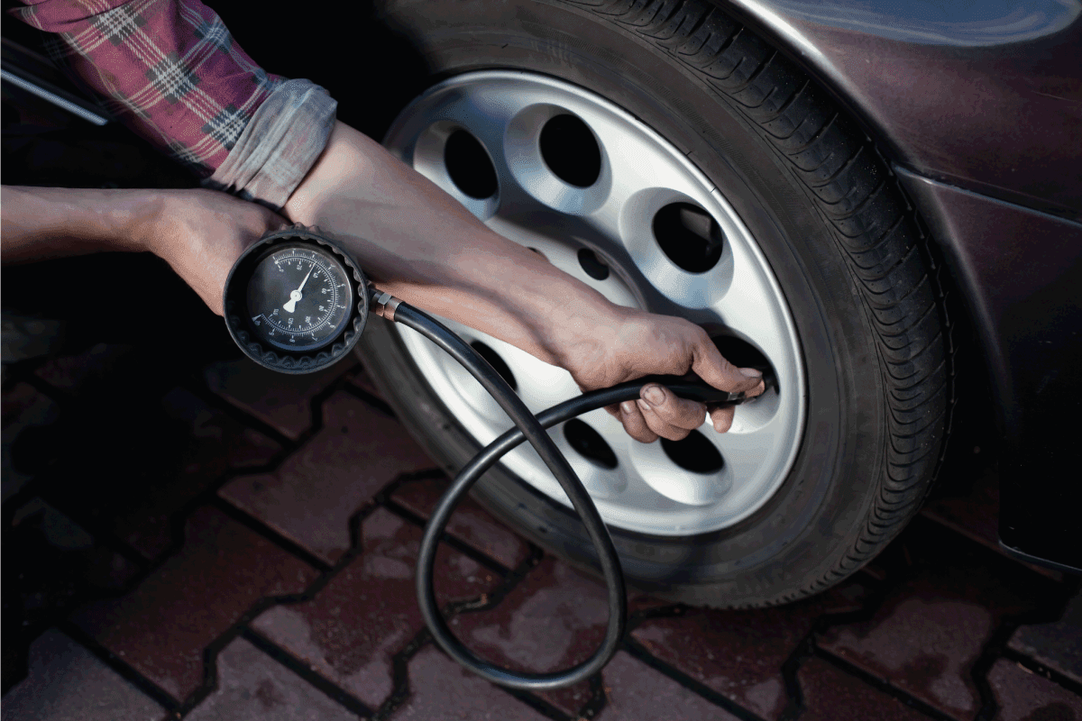 man wearing long sleeves checking tire pressure using long gauge. How To Check Tire Pressure On A Genesis G70