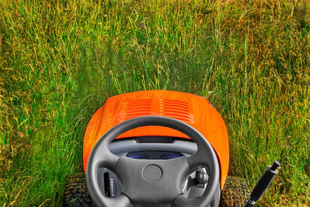 over the top of a riding lawnmower into tall grass and weeds