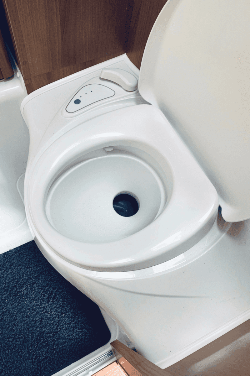 white toilet for a recreational vehicle with blue matting and wood trim