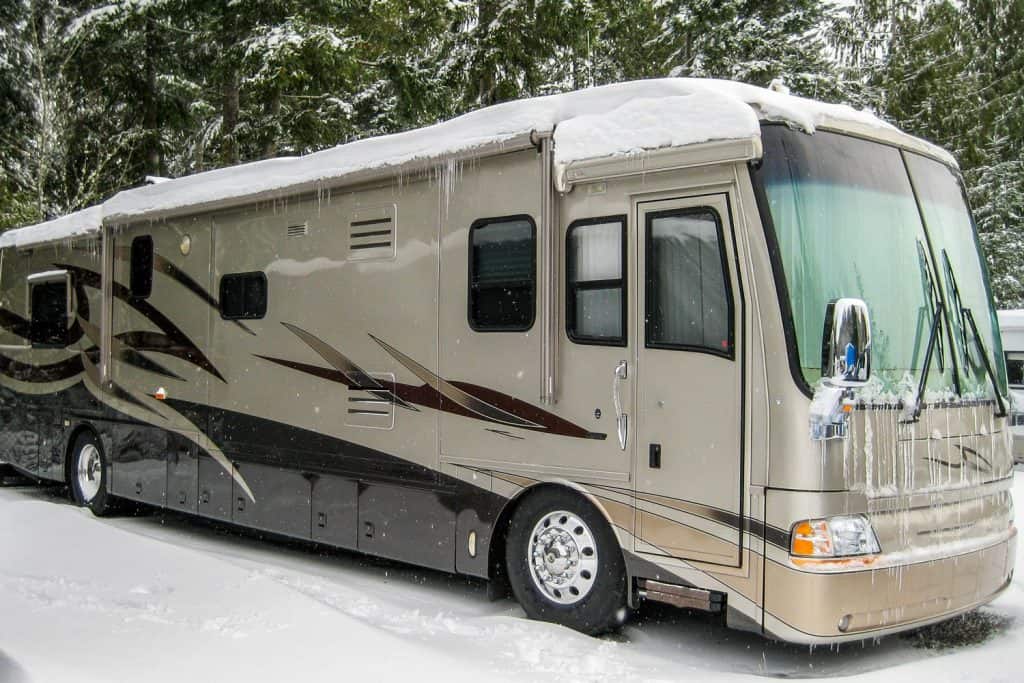 A class A motorhome covered in snow at the camping ground of a Ski park