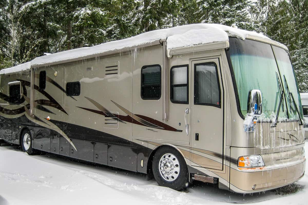 A class A motorhome covered in snow at the camping ground of a Ski park, Should RV Batteries Be Removed In Winter?