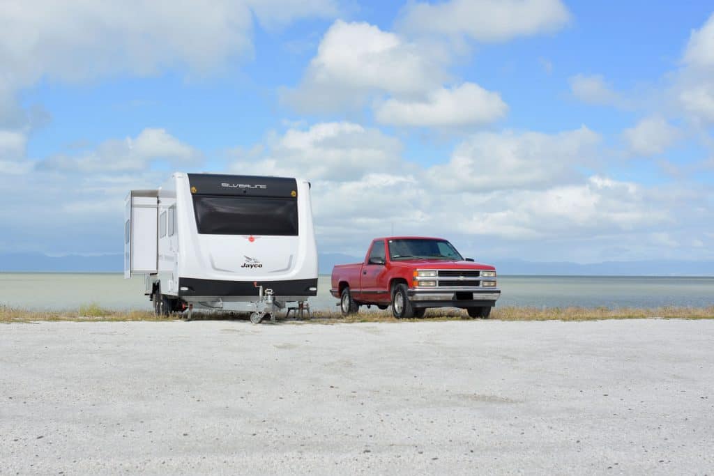 A Jayco fifth wheel trailer parked next to a red Ford pickup truck