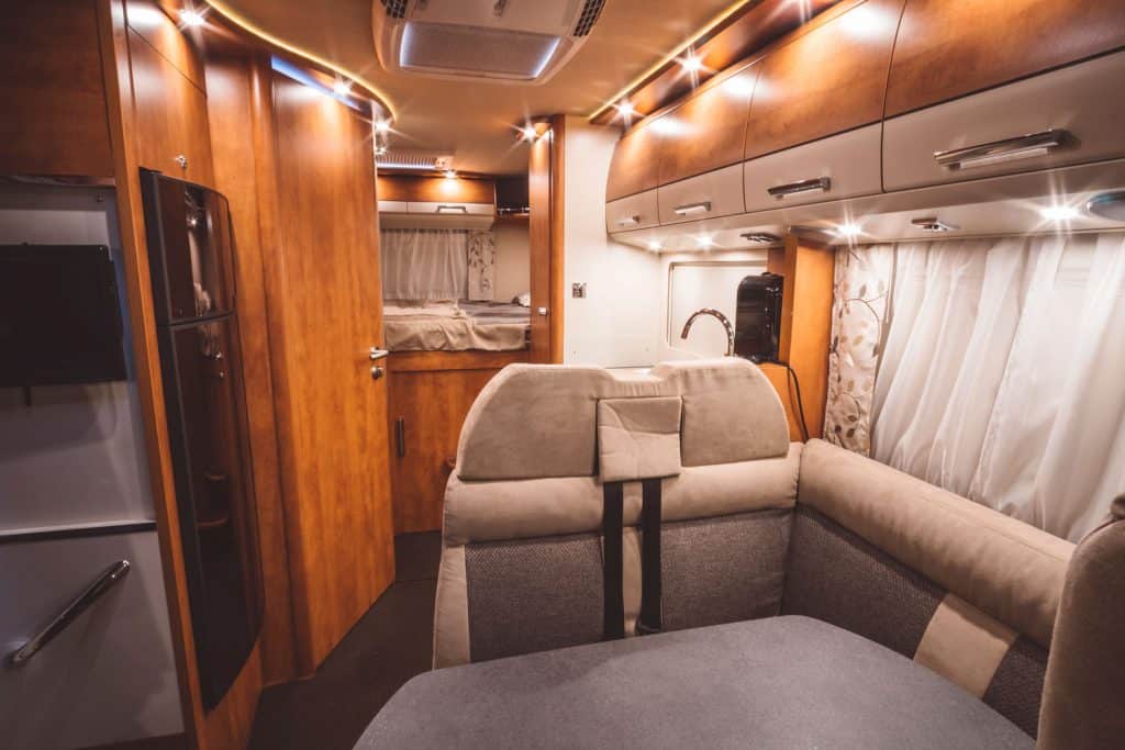 A brightly lit luxurious RV interior with wooden cabinets and shelves