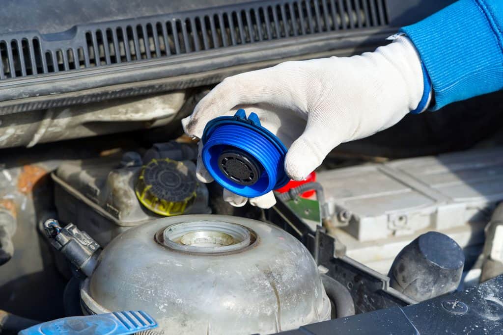 A car mechanic opening the coolant cover of the cars engine