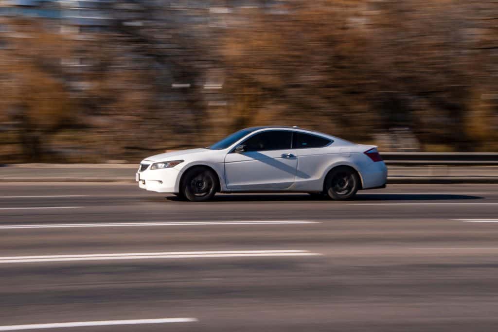A fast moving white Honda Accord on the highway
