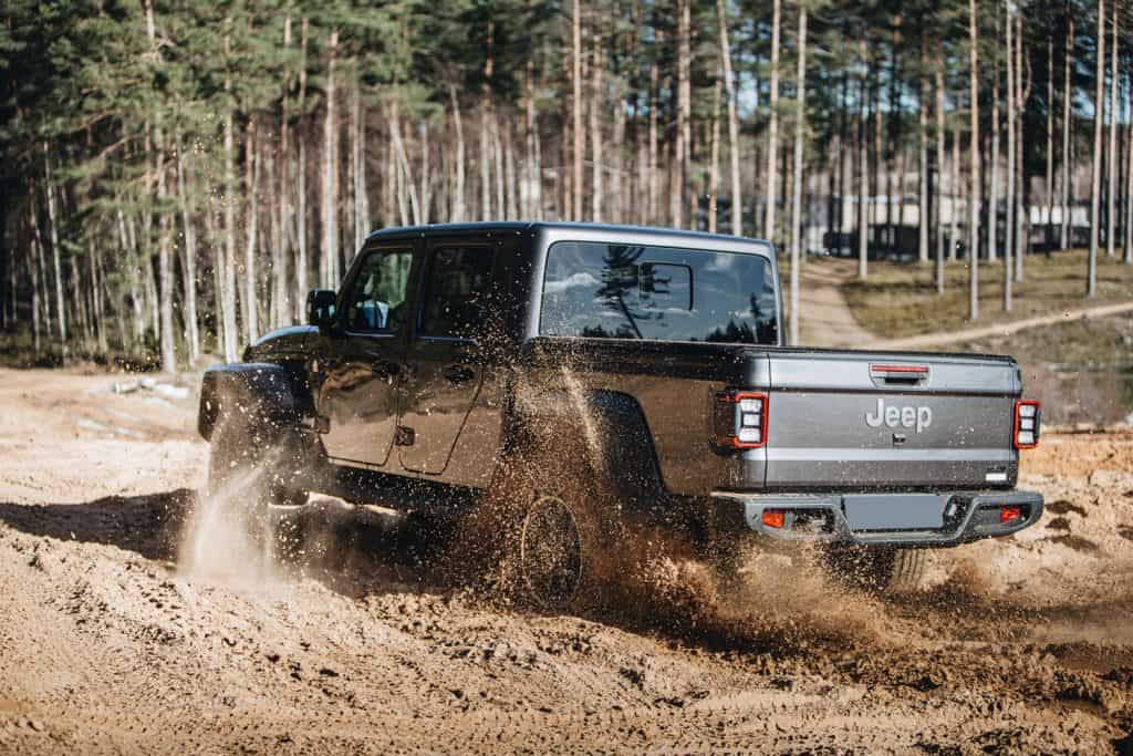 A gray Jeep Gladiator trekking on a dirt road