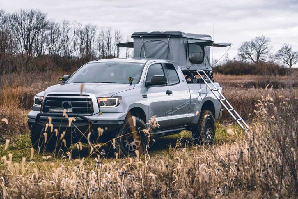 A gray Toyota Tacoma parked in a large field for camping