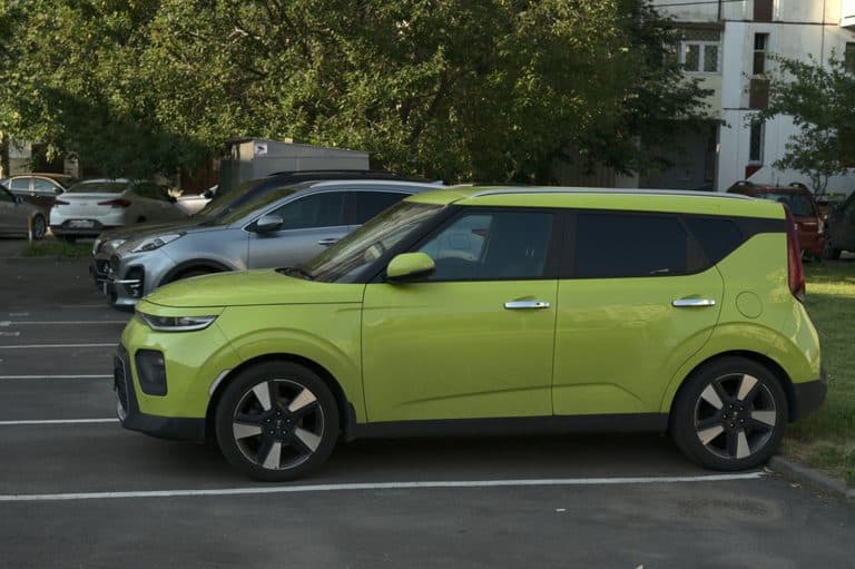 A green kia soul car is parked on the street, How Big Is A Kia Soul?