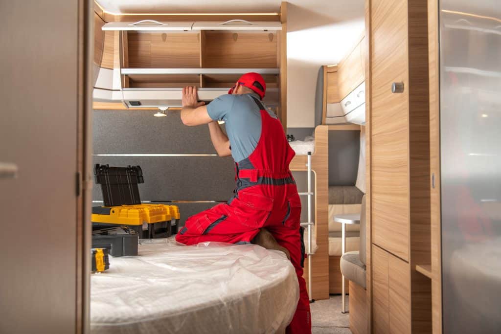 A home interior worker installing wooden shelves into the motorhome