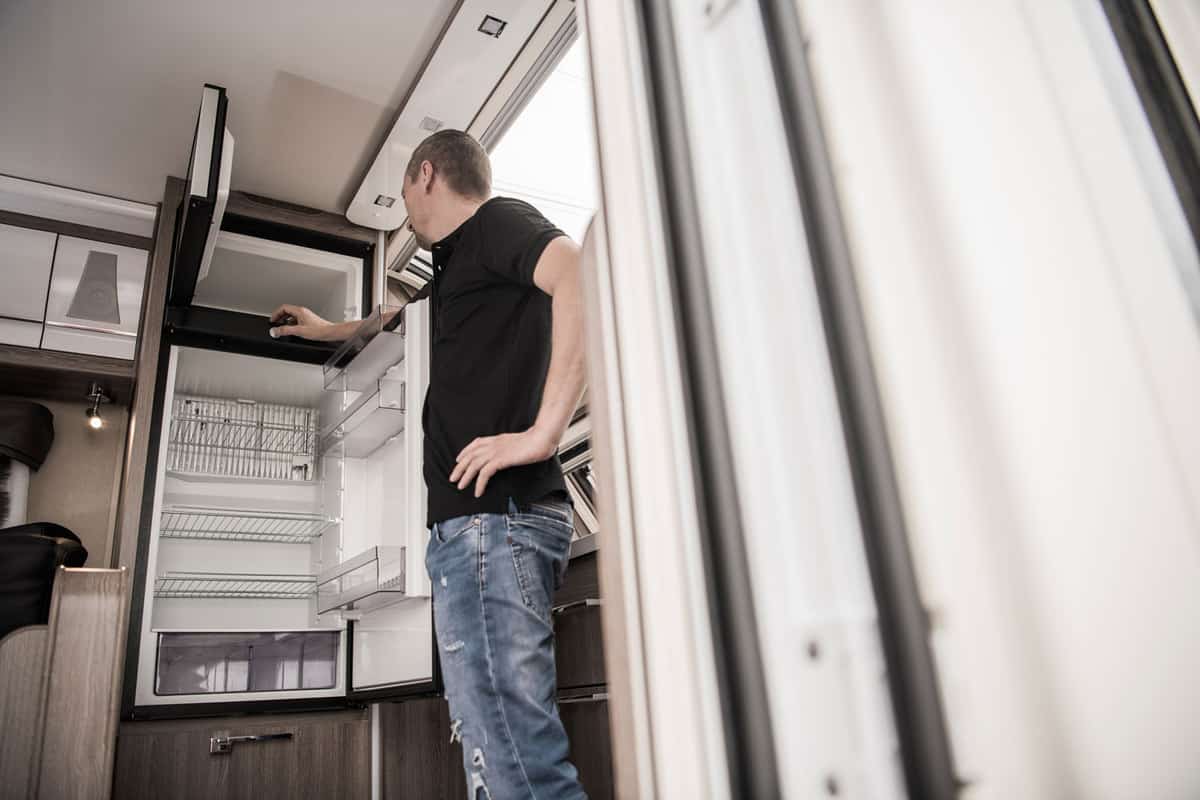A home service repairman checking the broken fridge of an RV