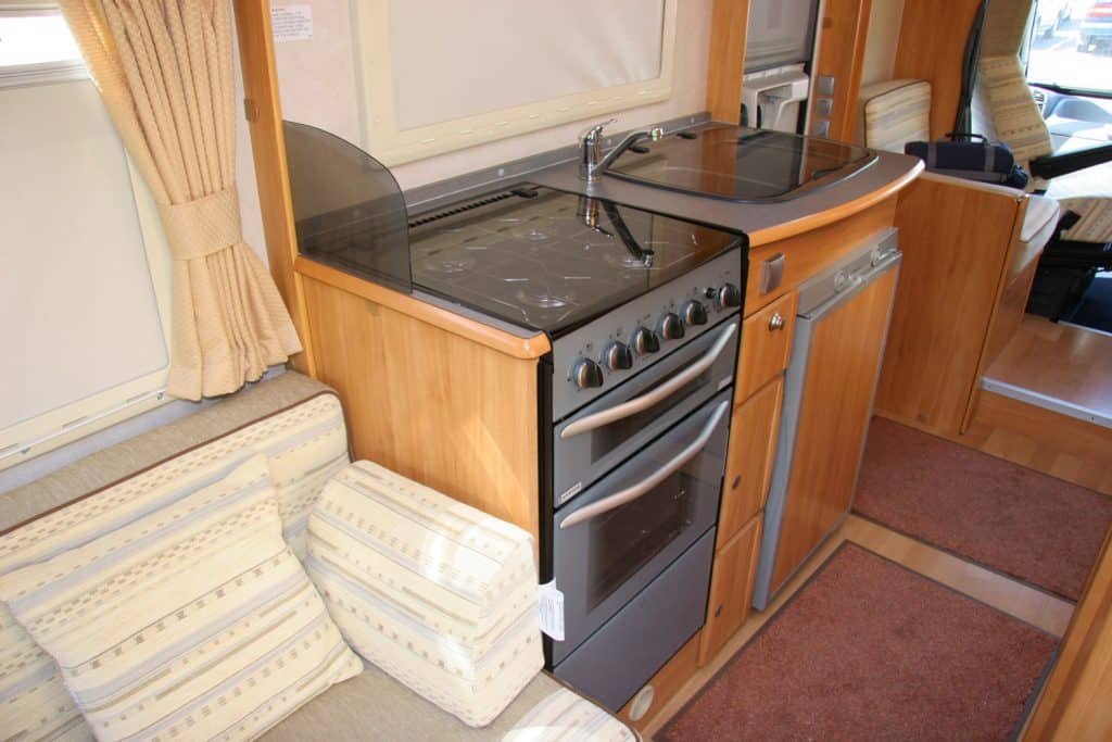 A small RV oven placed next to a fridge