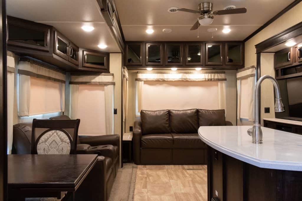 A spacious and luxurious motorhome interior of an RV with dark wooden cabinets and a white countertop
