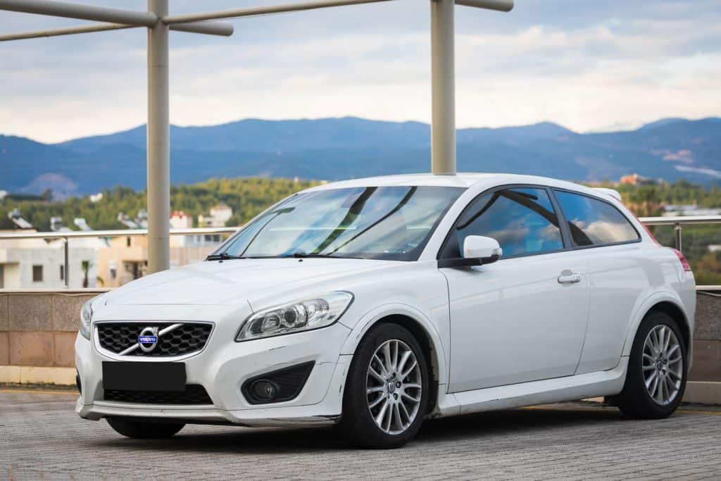 A white Volvo C30 parked on a rooftop parking area