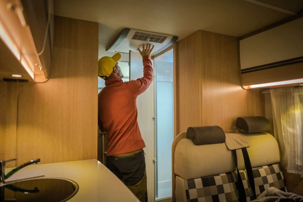 A worker installing an air conditioning unit inside the RV