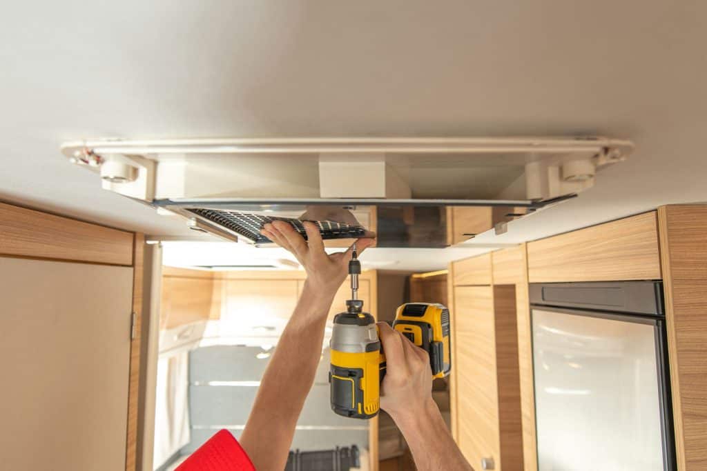 A worker installing an air conditioning unit inside an RV