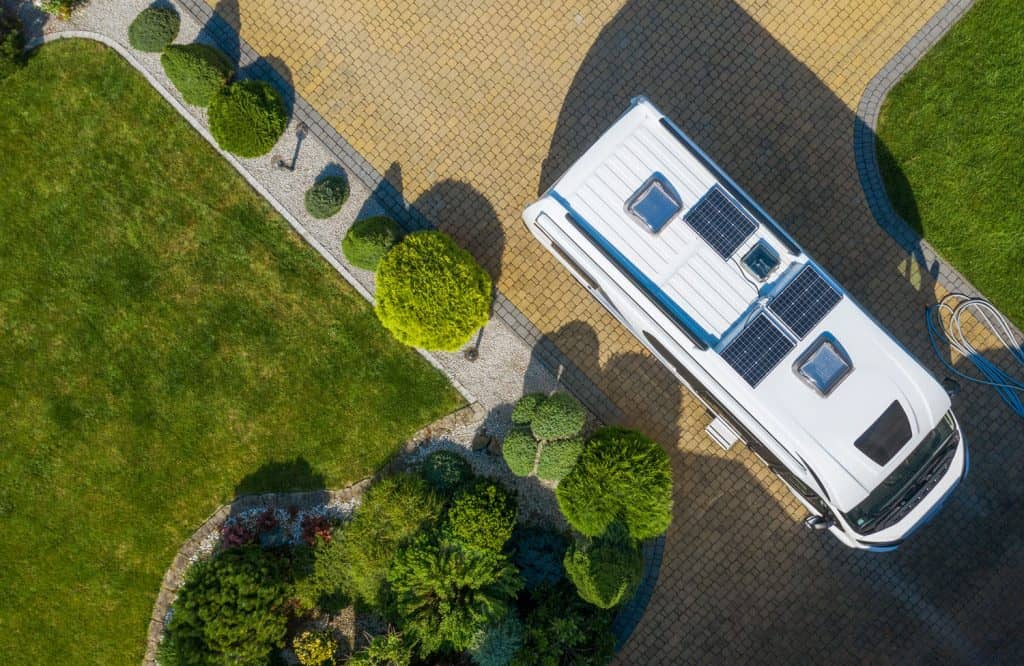 Camping and Tourism Theme. Modern Camper Van with Solar Panels Installed Staying on Cobble Stone Driveway Awaiting New Destination. Aerial View