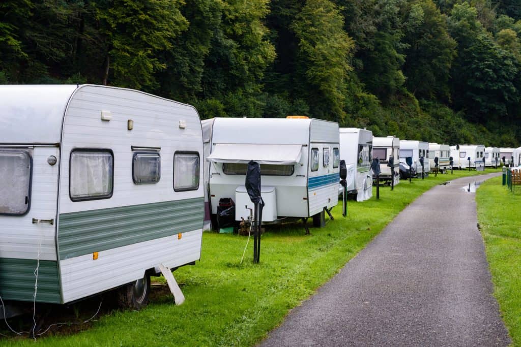 Caravans or camper trailers set on the river side of river Semois in camp site or camping in Ardennes region of Wallonia in Belgium.