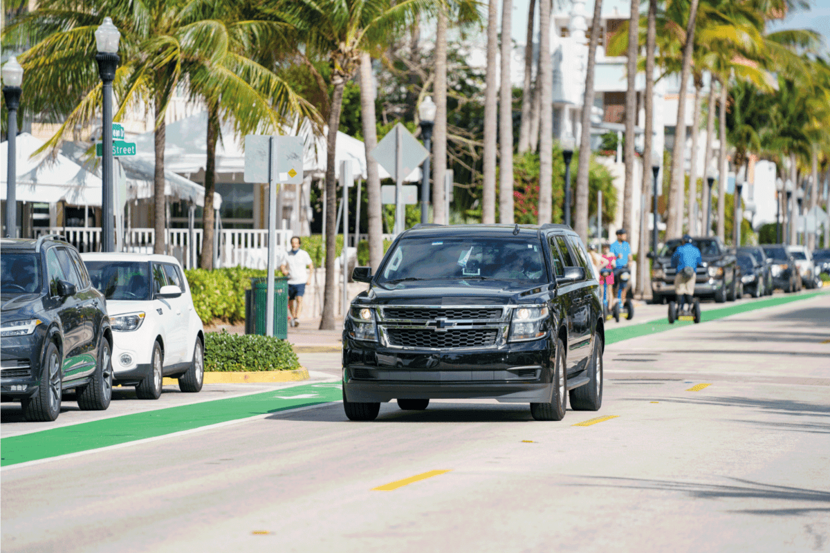 Chevy Suburban lux uber suv or lyft rideshare vehicle cruising Miami Beach Ocean Drive