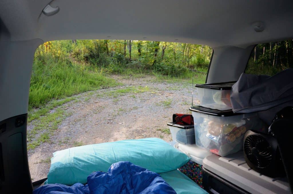 Looking over mattress, pillow, and quilt out tailgate of car camping setup