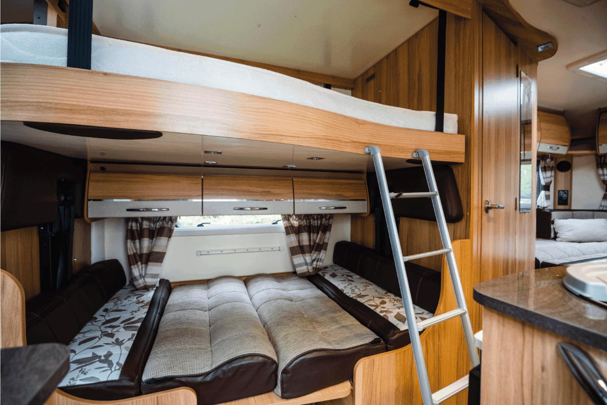 Luxury large open plan motor home interior with sleeping area for several occupants. Skylight and windows letting in a lot of daylight