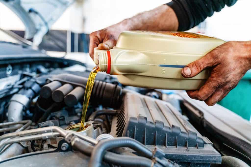 Pouring oil to car engine. Fresh motor oil poured during an oil change to a car