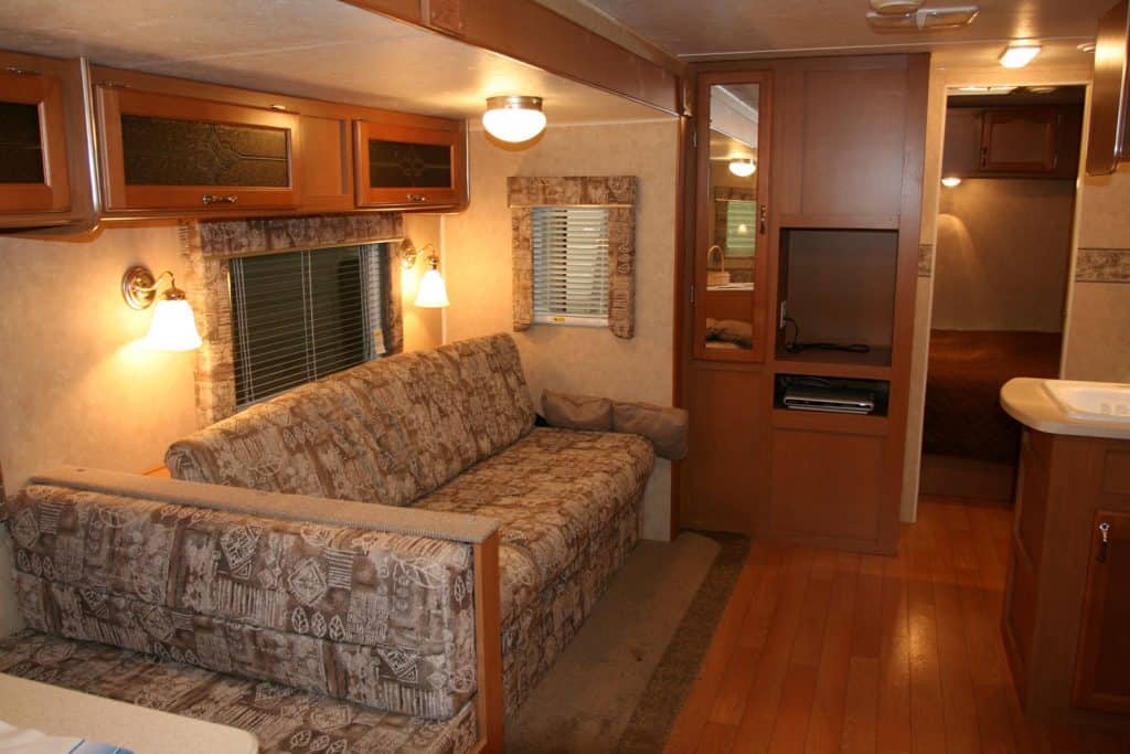 Rustic inspired motorhome interior with wooden flooring, classic designed sofas and wooden shelves and lamps
