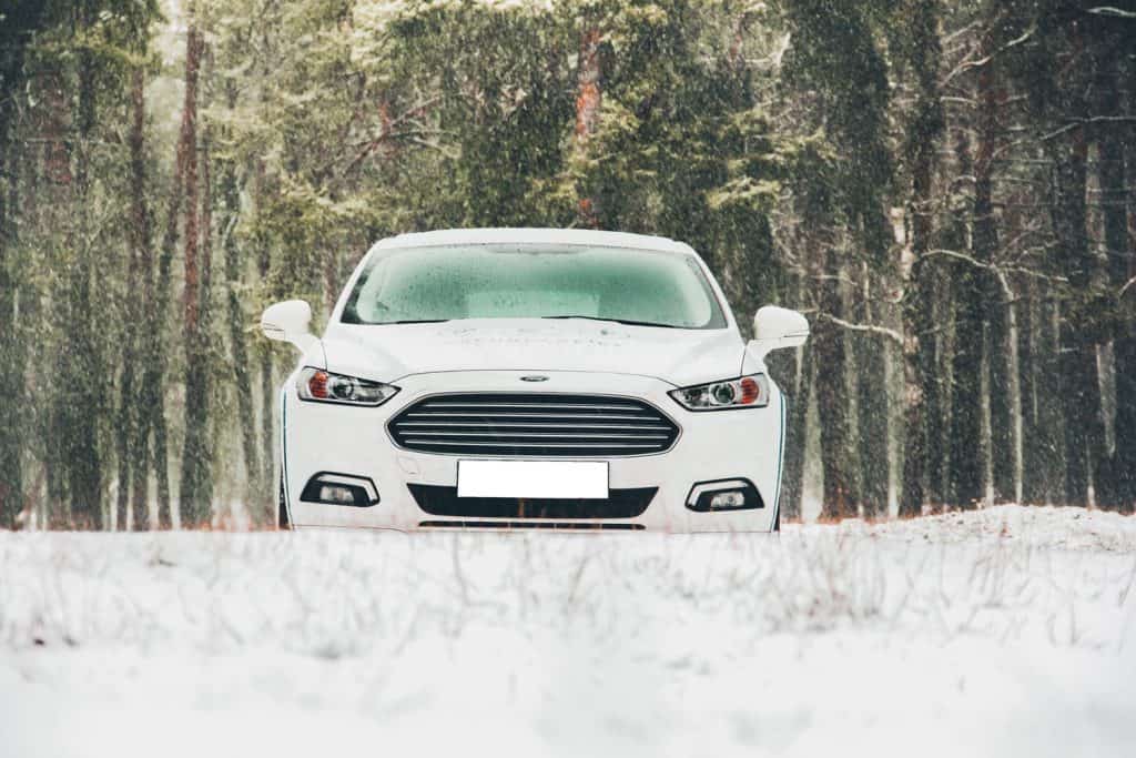 White Ford car in a snowy forest