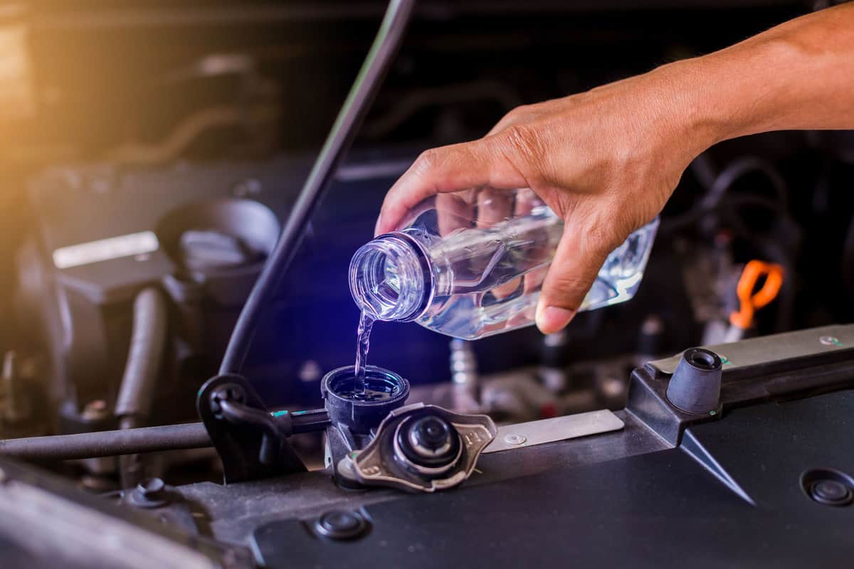 hands of mechanic check water in car radiator and add water to car radiator, service and maintenance of cars or vehicles