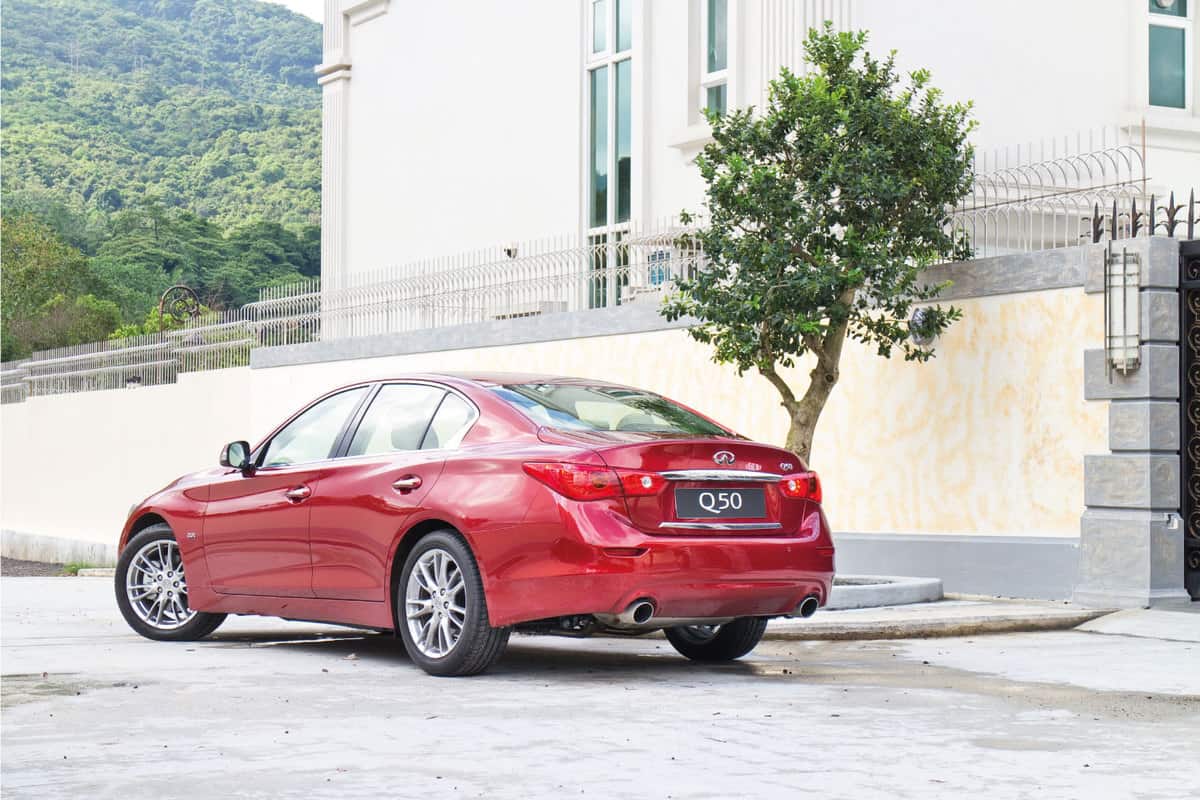 red infiniti Q50 parked beside a luxury house
