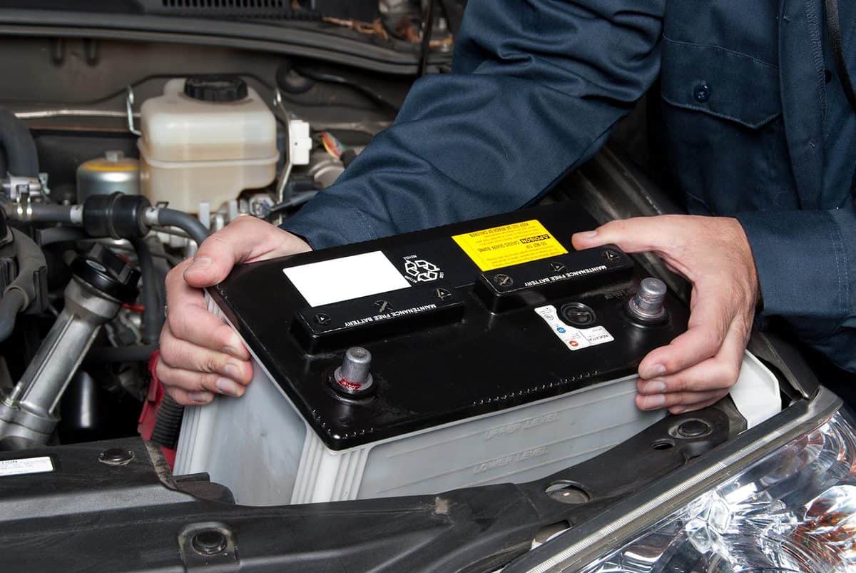 A car mechanic replaces a battery during maintenance