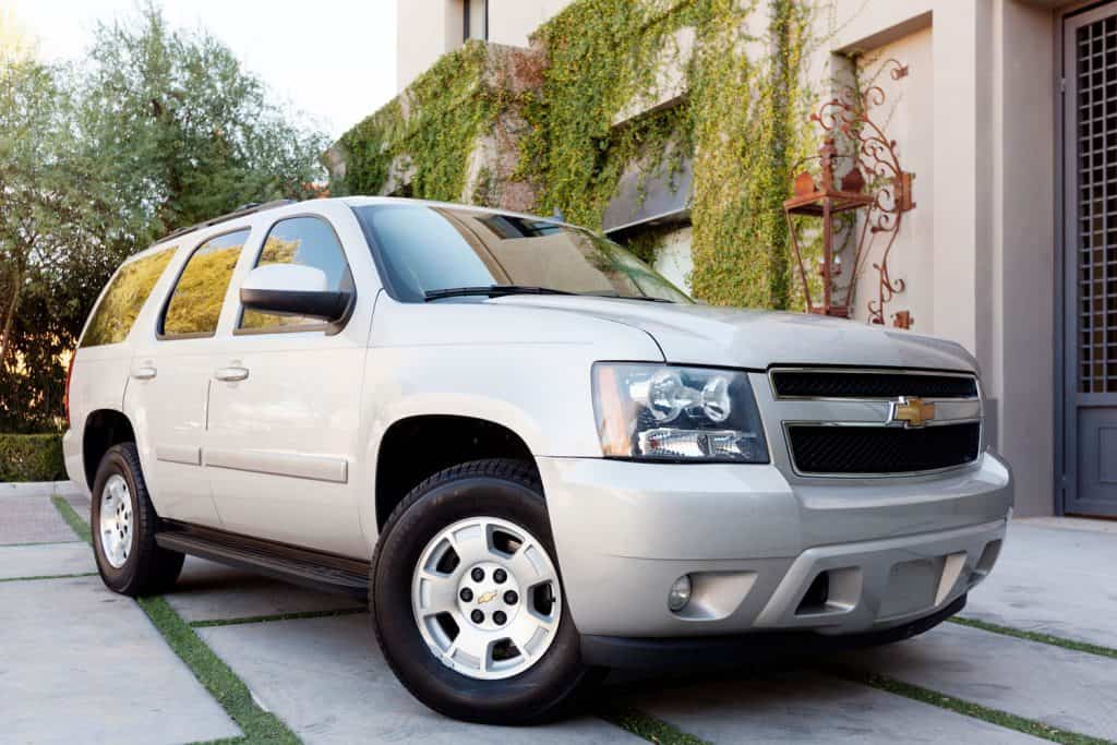 A gray Chevrolet Tahoe parked outside a house