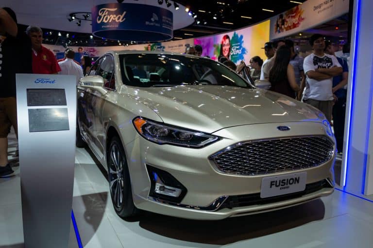 A light beige Ford Fusion Energi (American plug-in hybrid 4-door midsize sedan - 2nd Gen) displayed inside Ford pavilion, How To Open Ford Fusion Hood [Inc. When The Battery Is Dead]