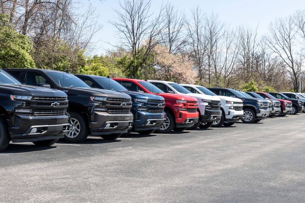 A line up of different trim levels of Chevrolet Suburban's and Silverado's at a dealership