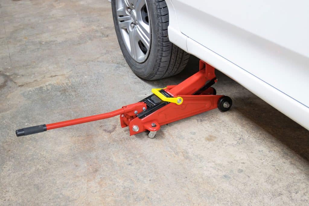 A red floor jack used in lifting the car