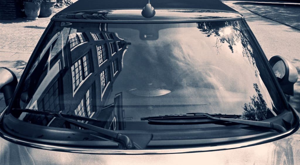 A typically Dutch building is reflected into the dashboard of a small car, in Amsterdam