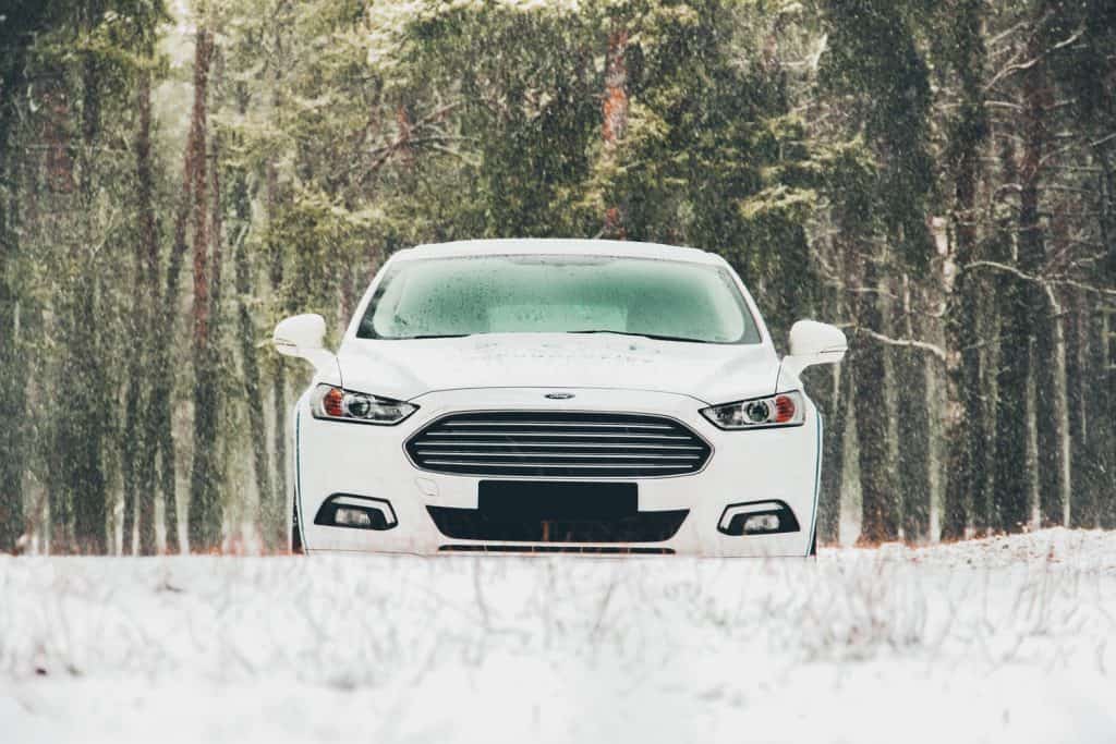 A white Ford Fusion trekking in the snow