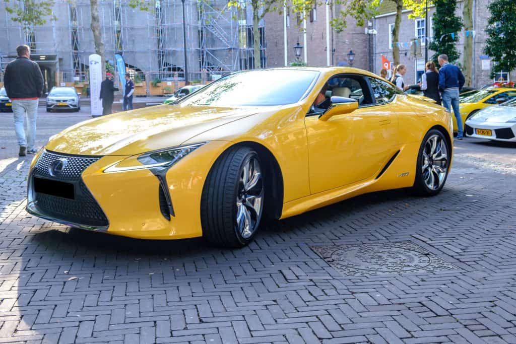A yellow LC500H photographed at an outdoor car show