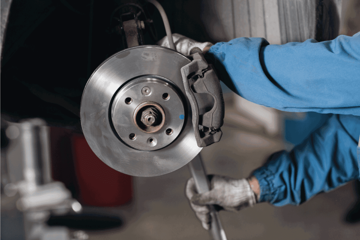 Brand new brake disc on car in a garage. Auto mechanic repairing a car.