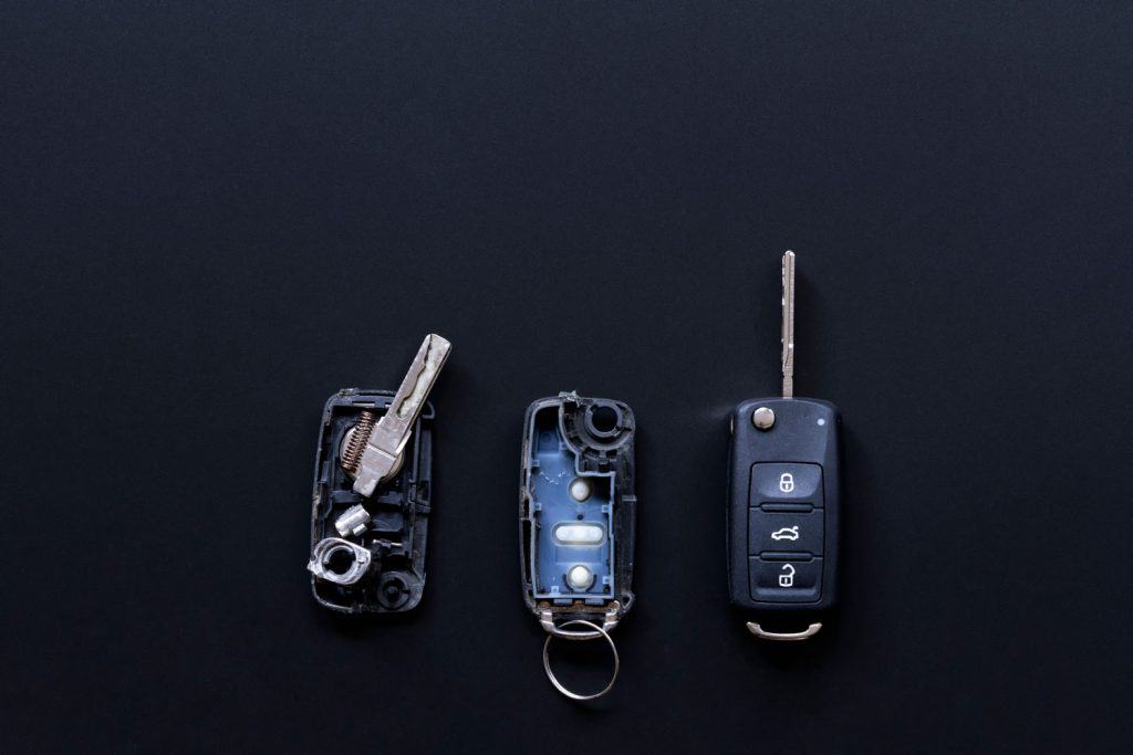 Broken or damaged remote key fob and new vehicle key on black dark grey background