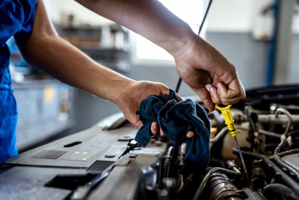 Car mechanic checking oil levels